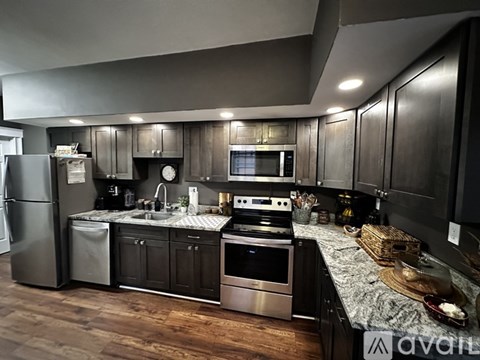 A modern kitchen with dark wood cabinets and stainless steel appliances.
