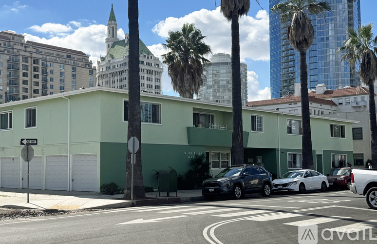 A street view of a green building with cars parked in front.