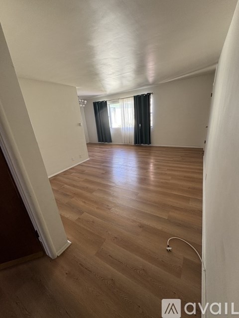 A room with wooden flooring and a window with curtains.