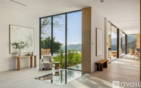 A modern living room with a glass table and a view of the outdoors.