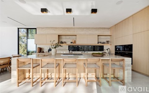 A modern kitchen with wooden chairs and countertops.