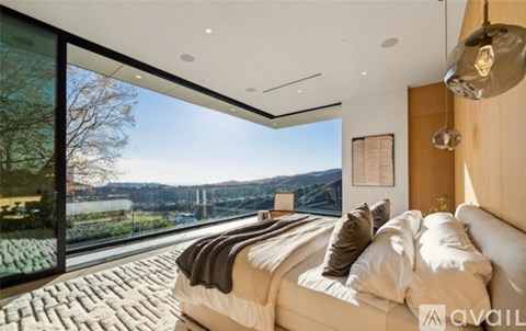 A bedroom with a large bed and a view of a lake and mountains through the window.