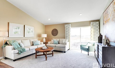 A living room with a white sofa, a wooden coffee table, and a green armchair.