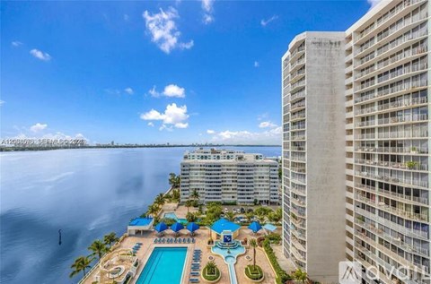 A large building with a pool and a view of the water.
