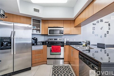 A kitchen with a refrigerator, microwave, oven, and sink.