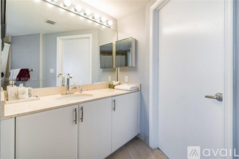 A bathroom with a vanity, mirror, and lights.