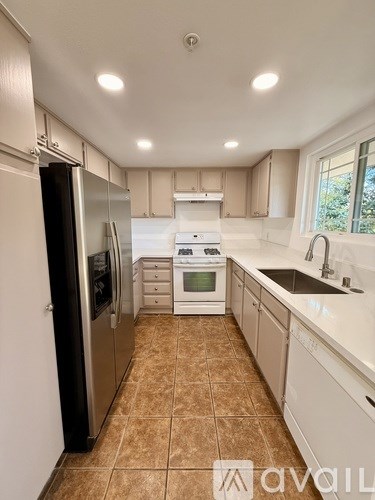 A kitchen with a black refrigerator and white cabinets.