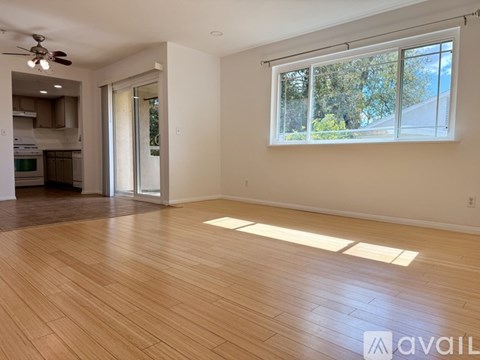 A spacious room with wooden flooring and a large window.