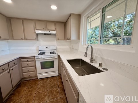 A kitchen with a white countertop and brown tiles.