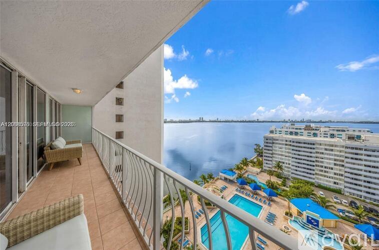 A balcony with a view of the ocean and a pool.