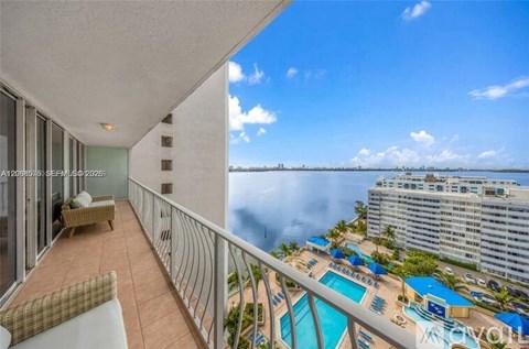 A balcony with a view of the ocean and a pool.
