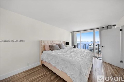 A bedroom with a large bed and a balcony overlooking the water.