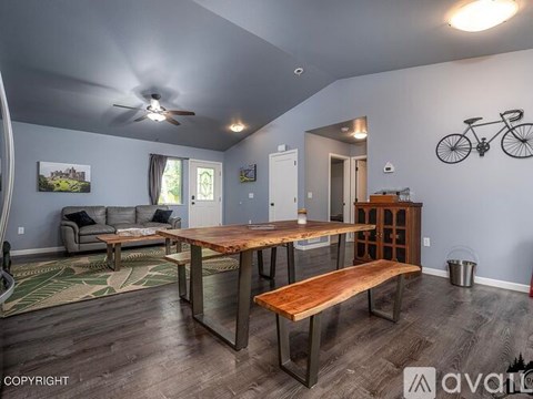 A dining room with a wooden table and bench, a ceiling fan, and a bicycle decoration on the wall.