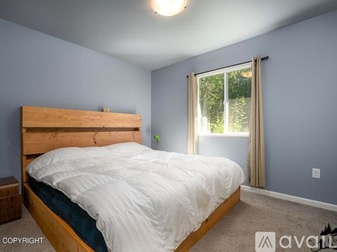 A bedroom with a bed, nightstand, and window.