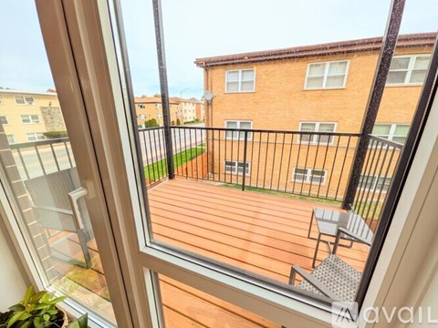 A balcony with a table and chairs overlooks a brick building.