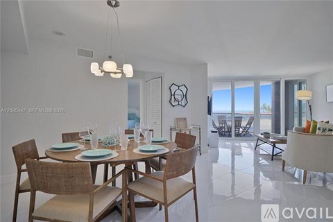 A dining room with a table set for six and a view of the ocean.