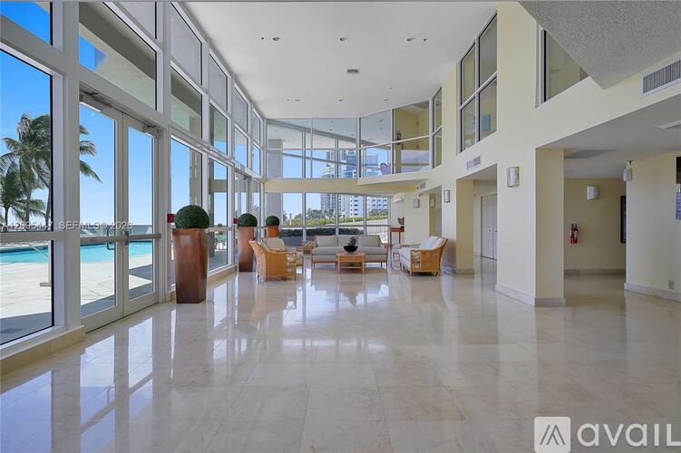 A spacious lobby with marble floors and large windows overlooking the pool.