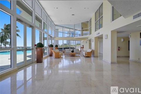 A spacious lobby with marble floors and large windows overlooking the pool.