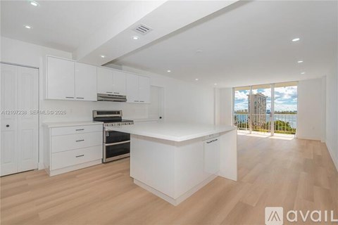 A spacious kitchen with white cabinets and a wooden floor.