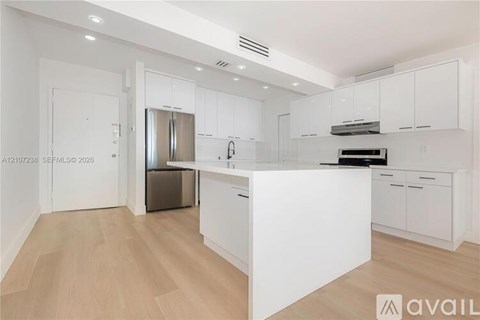 A modern kitchen with white cabinets and a wooden floor.