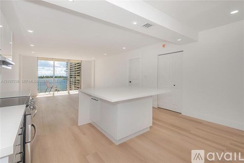 A modern kitchen with white cabinets and a wooden floor.