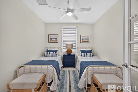 A bedroom with two beds and a ceiling fan.
