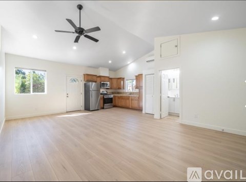 A spacious room with wooden flooring and a ceiling fan.