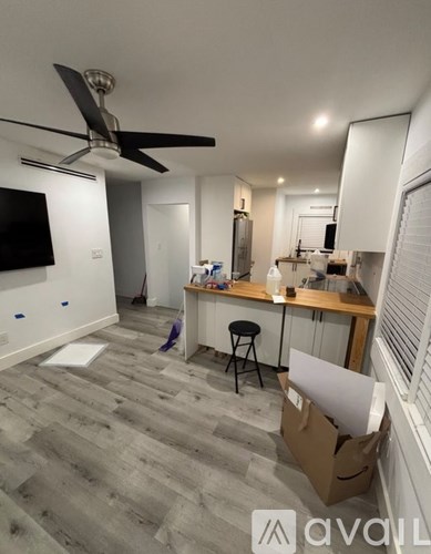 A room with a ceiling fan and a kitchen area with a table and chairs.