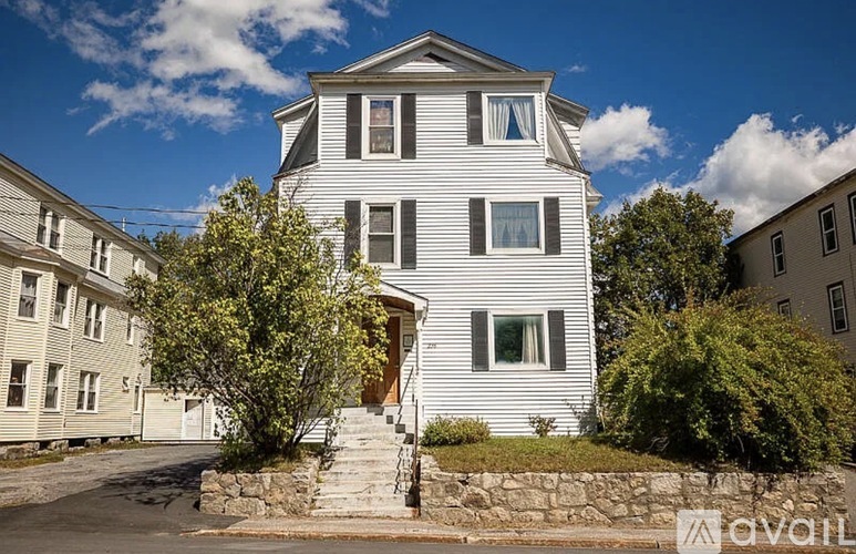 A large white house with a stone staircase leading to the front door.
