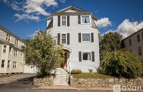 A large white house with a stone staircase leading to the front door.