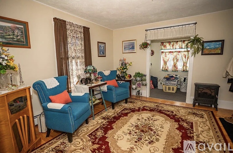 A living room with two blue chairs and a rug.