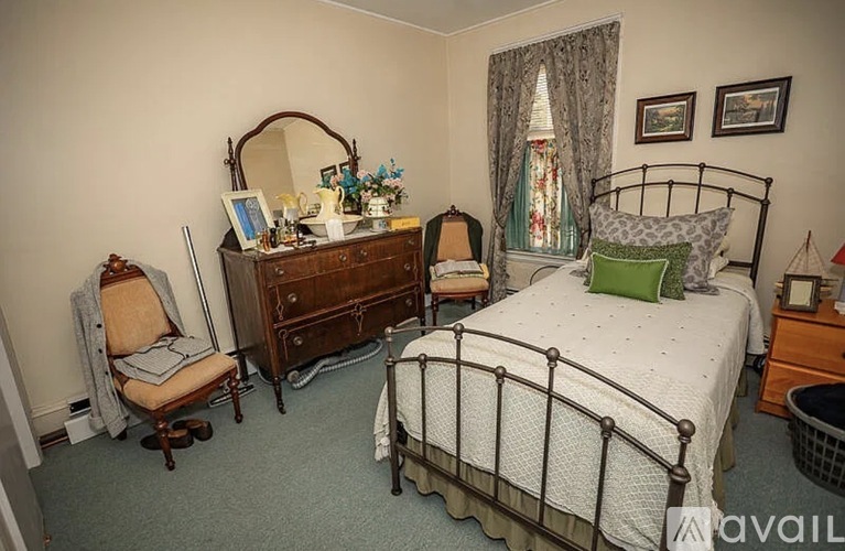 A bedroom with a bed, chair, and vanity.
