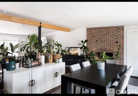 A dining room with a black table and white chairs.