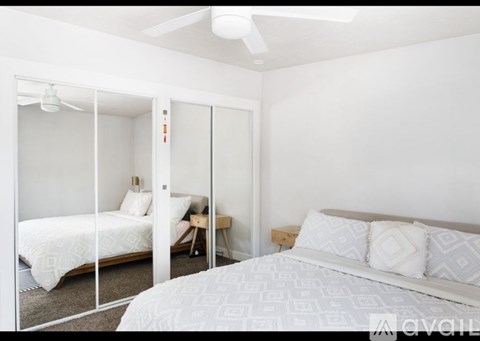 A bedroom with a bed, a chair, and a ceiling fan.