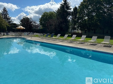 A pool with chairs around it and trees in the background.