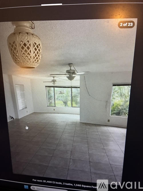 A room with a ceiling fan and a window overlooking greenery.