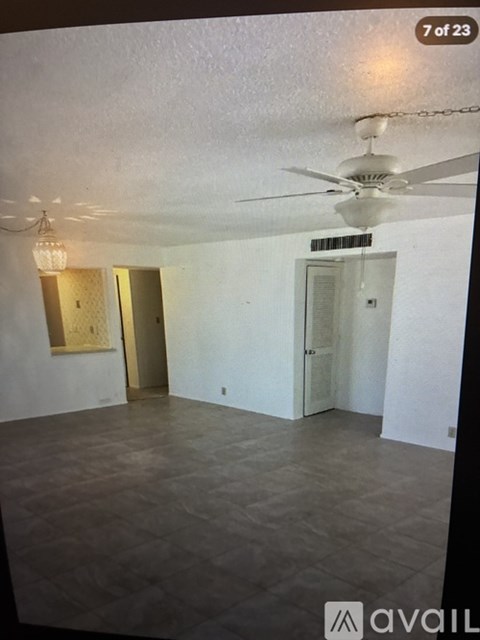 A room with a ceiling fan and a painting on the wall.