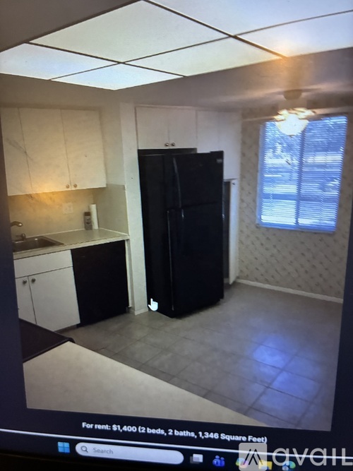 A black refrigerator in a kitchen with white cabinets.