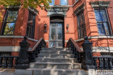 A red brick building with a black staircase leading to the front door.