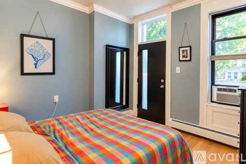 A bedroom with a bed and a framed picture hanging on the wall.