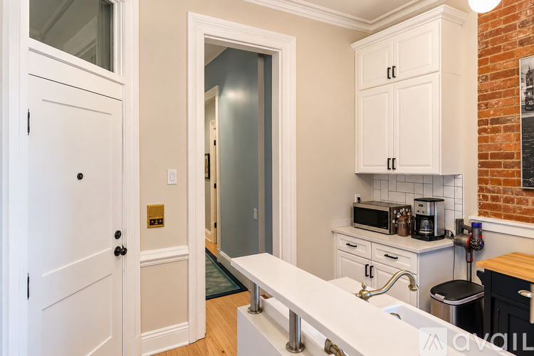 A kitchen with white cabinets and a brick wall.