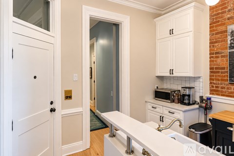 A kitchen with white cabinets and a brick wall.