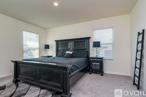 A bedroom with a black bed and a wooden floor.