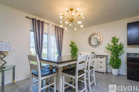 A dining room with a glass table and chairs, a chandelier, and a television.