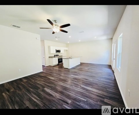 A spacious room with a ceiling fan and wooden flooring.