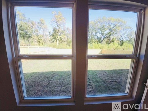 A window with a view of a grassy field and trees.