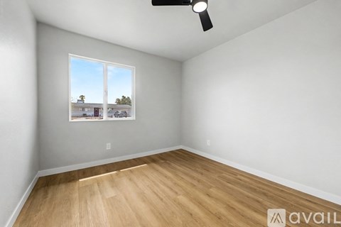 A room with a fan and a window showing a view of a building and trees.