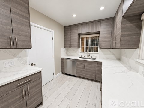 A modern kitchen with wooden cabinets and a marble countertop.