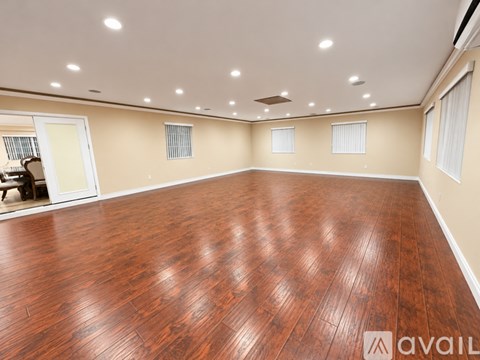 A spacious room with wooden flooring and recessed lighting.