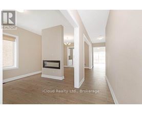A spacious room with a fireplace and wooden flooring.